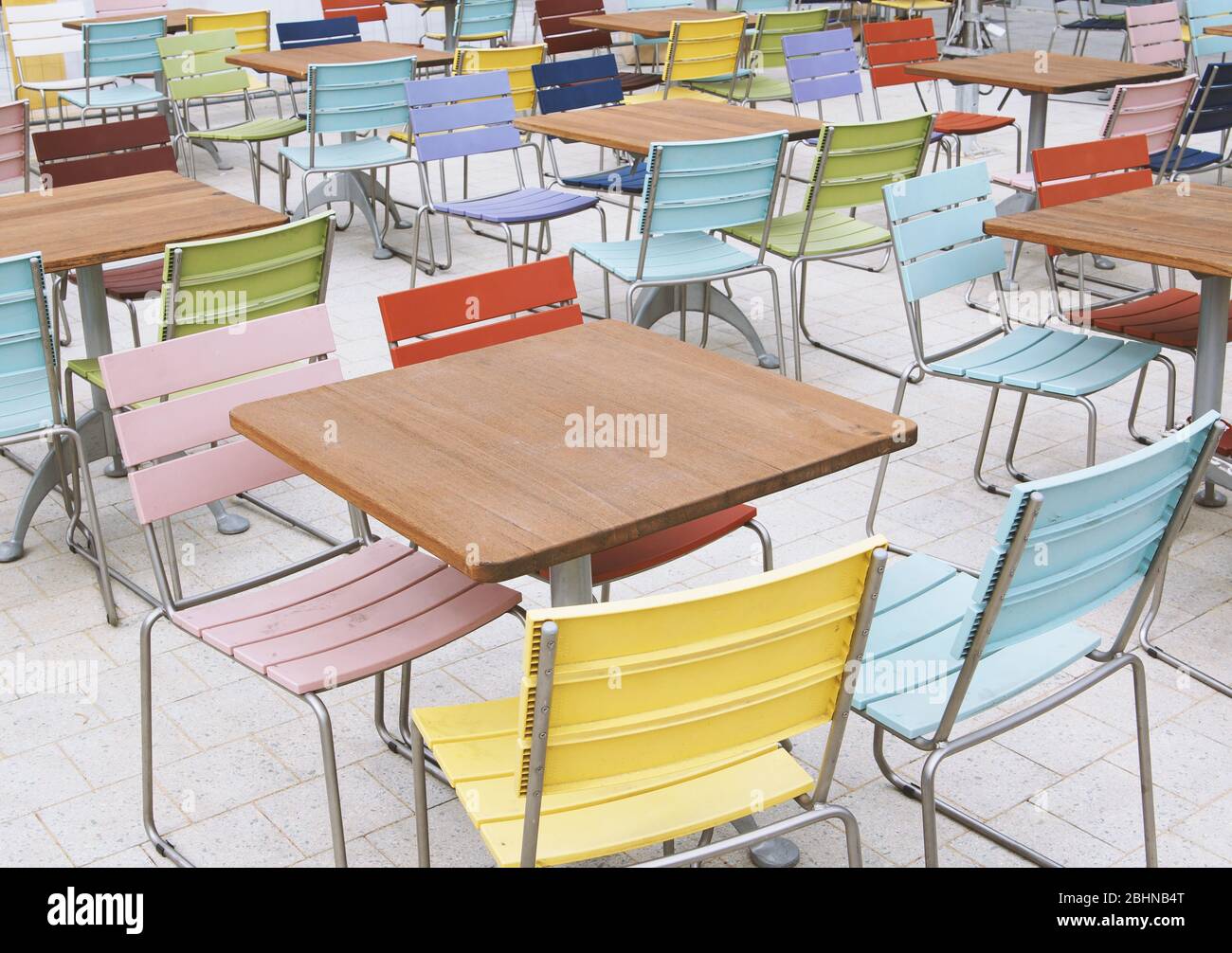 empty deserted street cafe or outdoor restaurant tables with multicolored chairs - off season or economy crisis concept Stock Photo