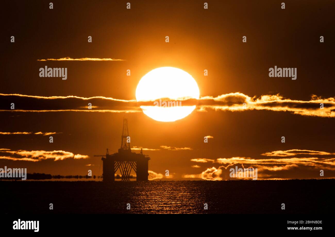 The sun rises behind a redundant oil platform moored in the Firth of Forth near Kirkcaldy, Fife. Stock Photo