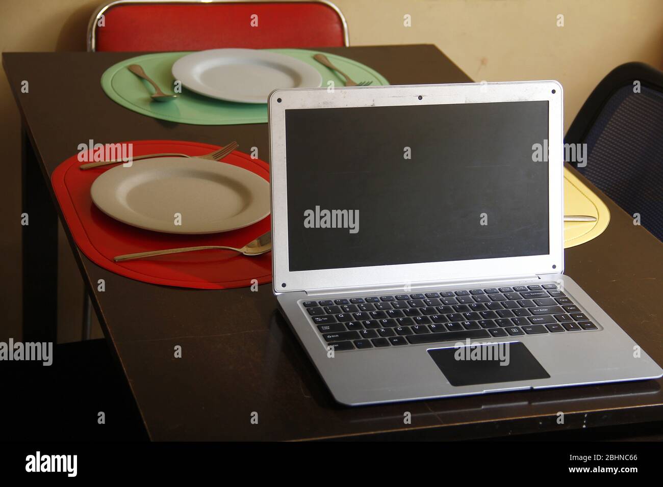 Photo of laptop computer, plates and utensils on a dining table Stock ...