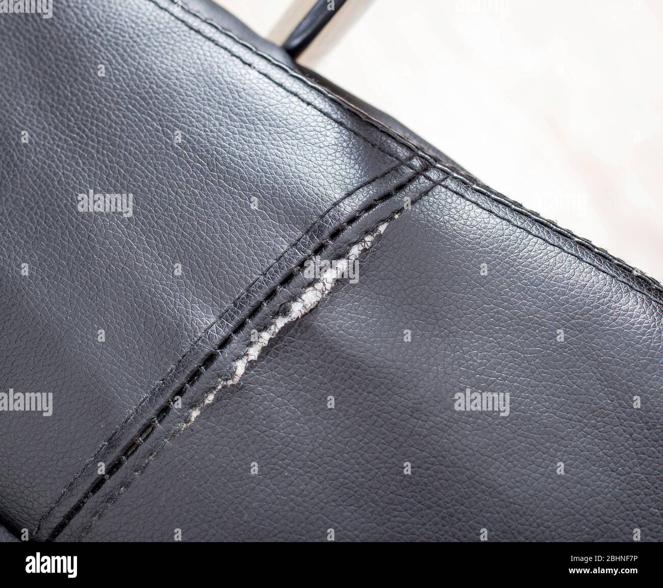 Torn and battered leather on a black office computer chair. Restoration