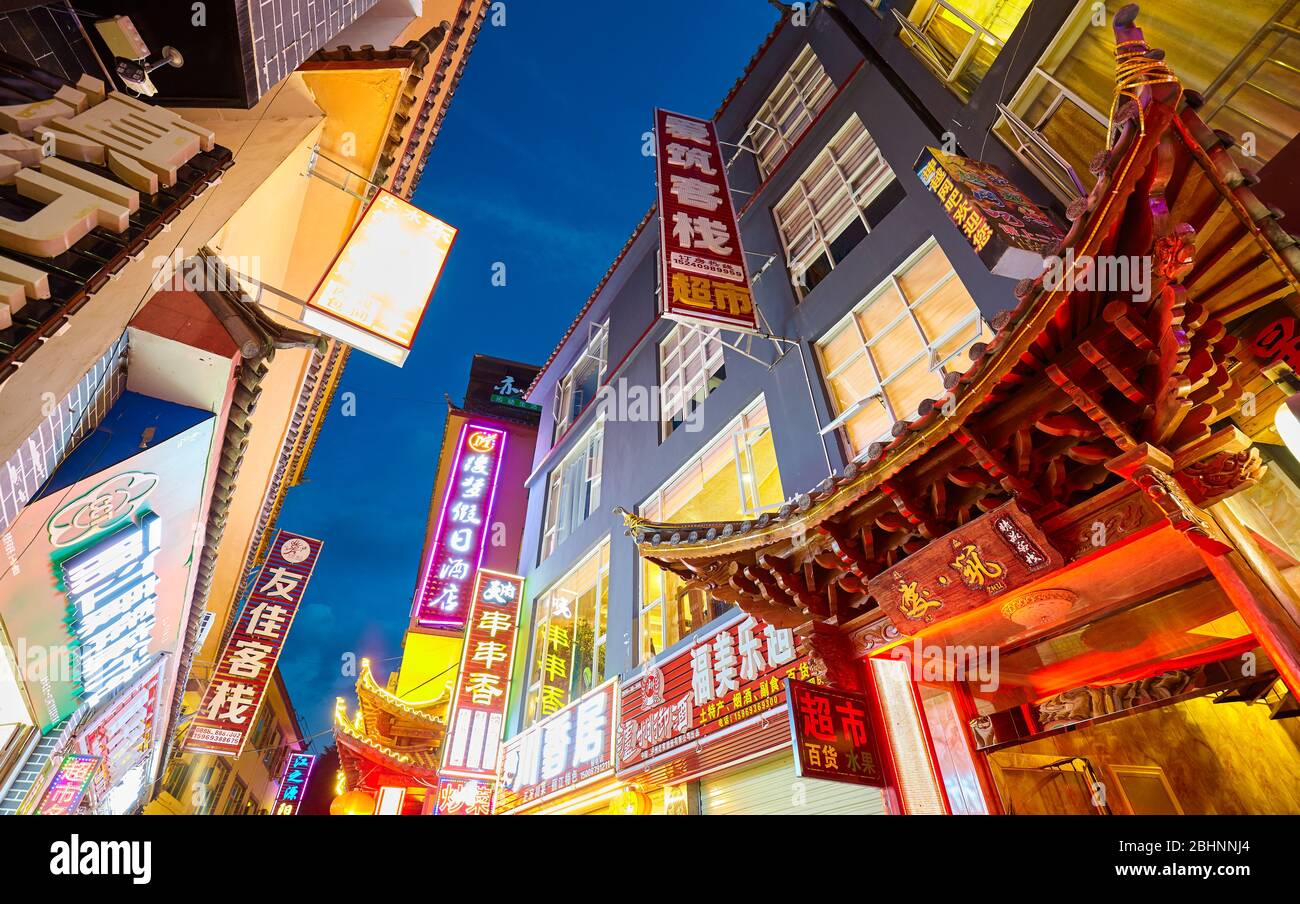 Lijiang, China - September 27, 2017: Looking up at buildings with advertising signs with Chinese characters at night. Stock Photo