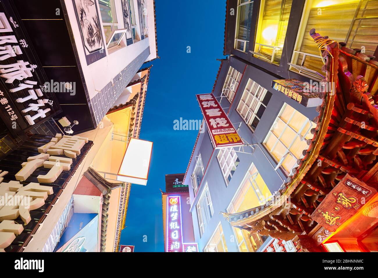 Lijiang, China - September 27, 2017: Looking up at buildings with advertising signs with Chinese characters at night. Stock Photo