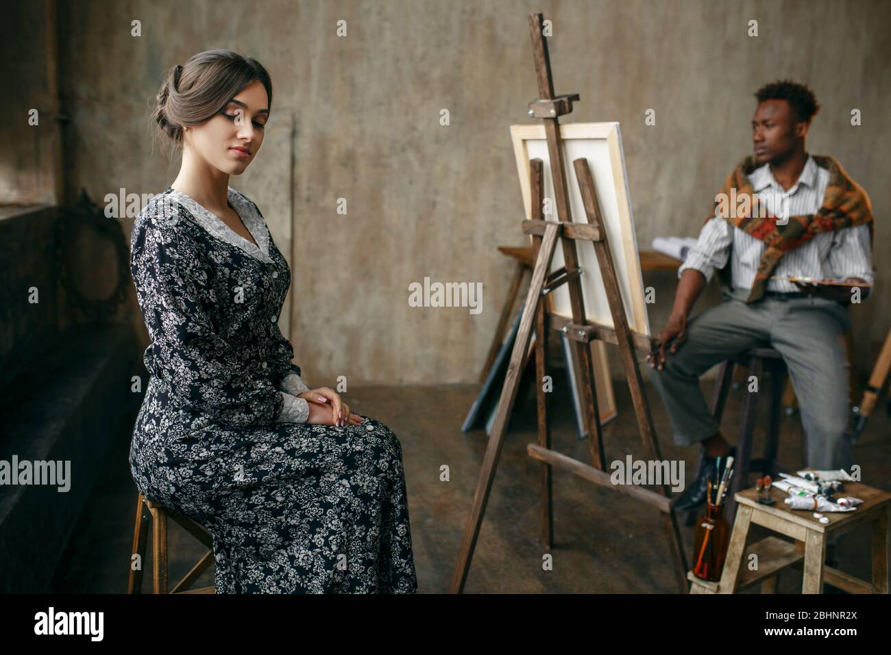 Painter with palette and brush draws female model Stock Photo