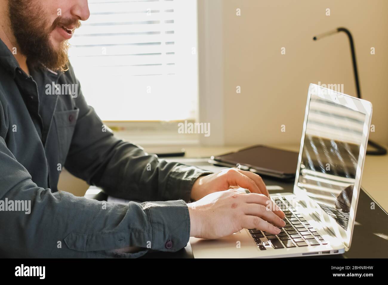 Bearded man chatting in social networks by laptop at office. Stock Photo