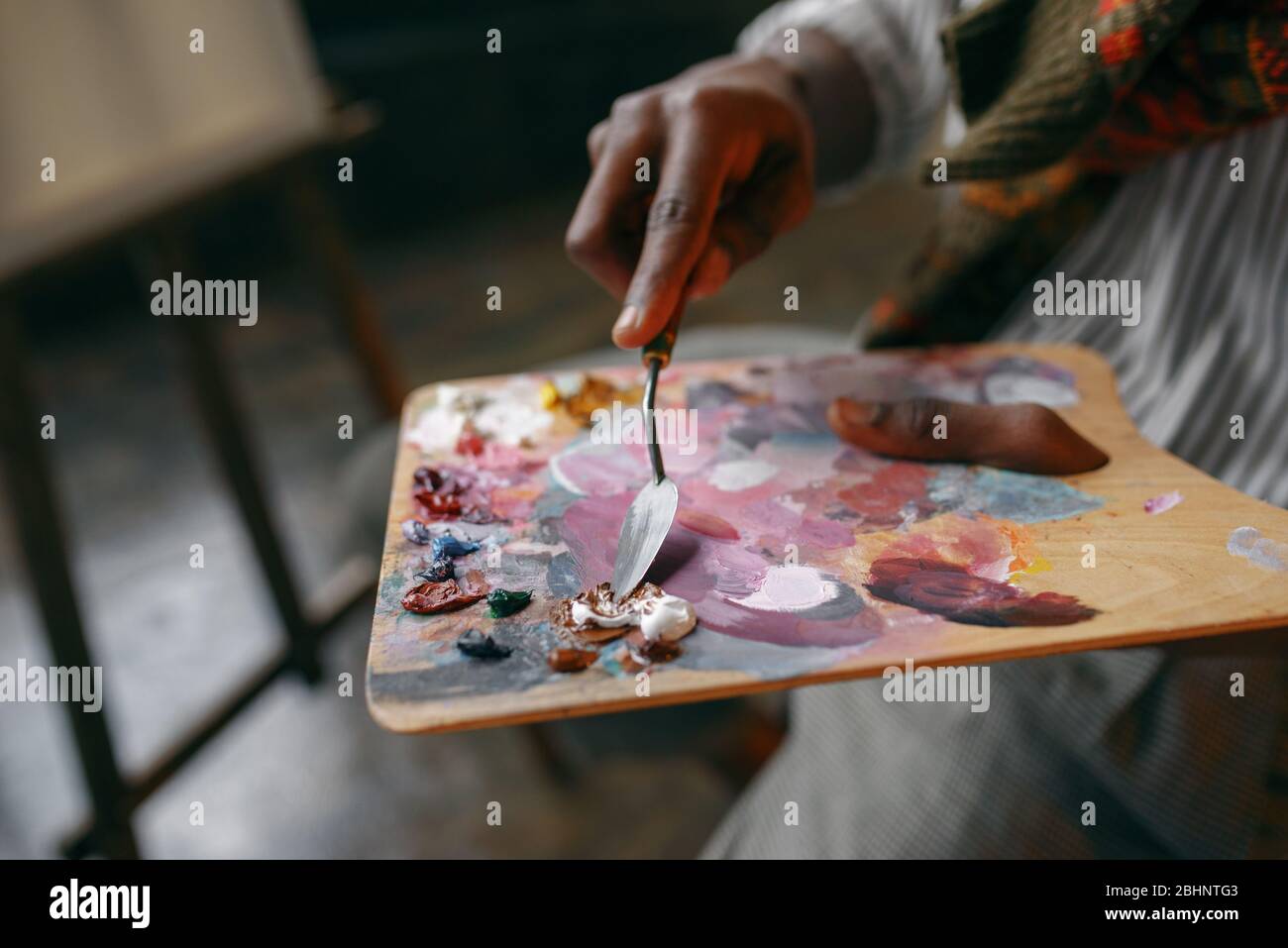 Painter holds brush and colorful paints on palette Stock Photo - Alamy