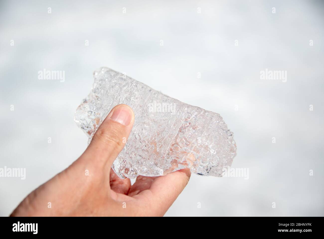 Hand holding a melting piece of ice on Athabasca glacier in Columbia Icefield, Jasper National park,  Rocky Mountains, Alberta, Canada Stock Photo