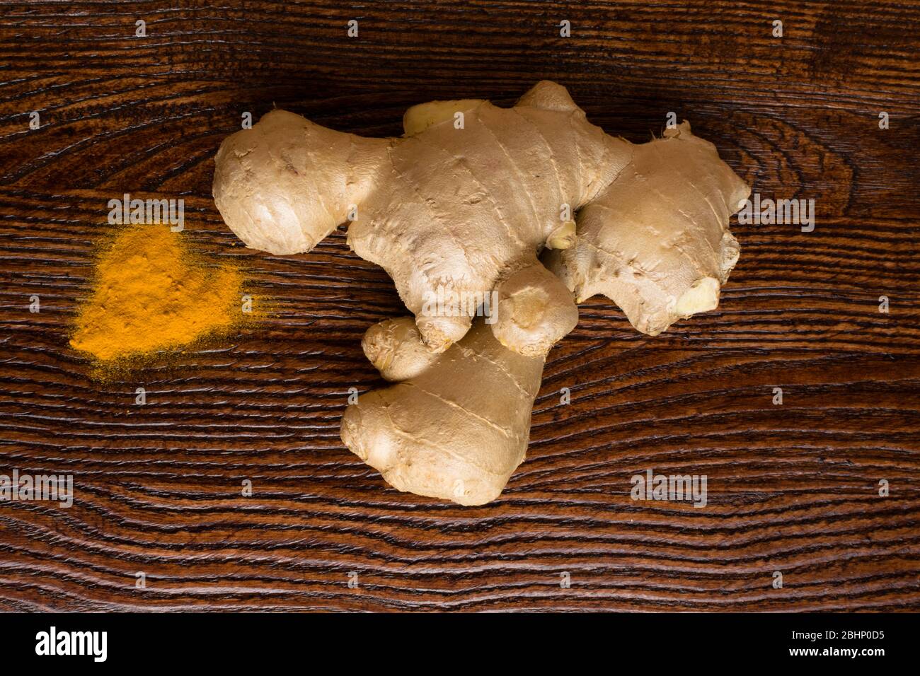 Fresh and organic ginger root and turmeric powder on wooden background