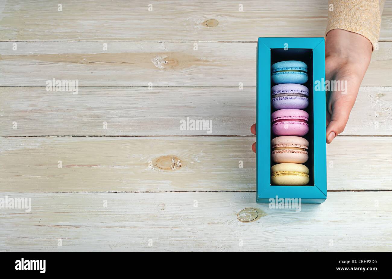 Female hand holds gift box with macaroons Stock Photo