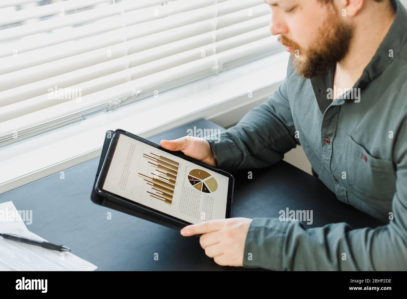 Businessman working with graphs and diagrams on tablet at office. Stock Photo