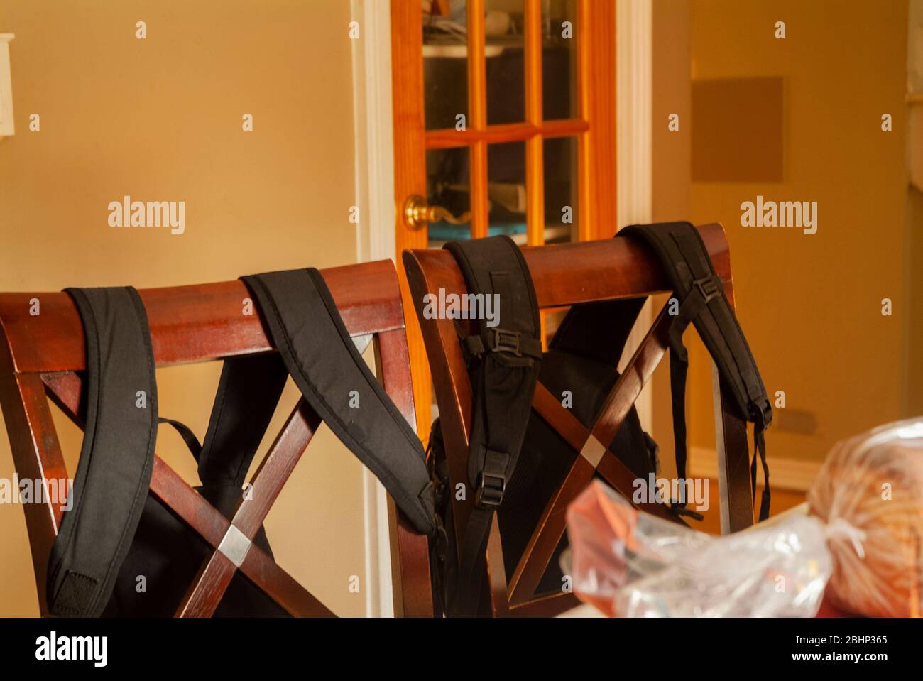 HOME SCHOOLING: Book bags hang on the back of kitchen chairs beside a picnic basket on a table. Stock Photo