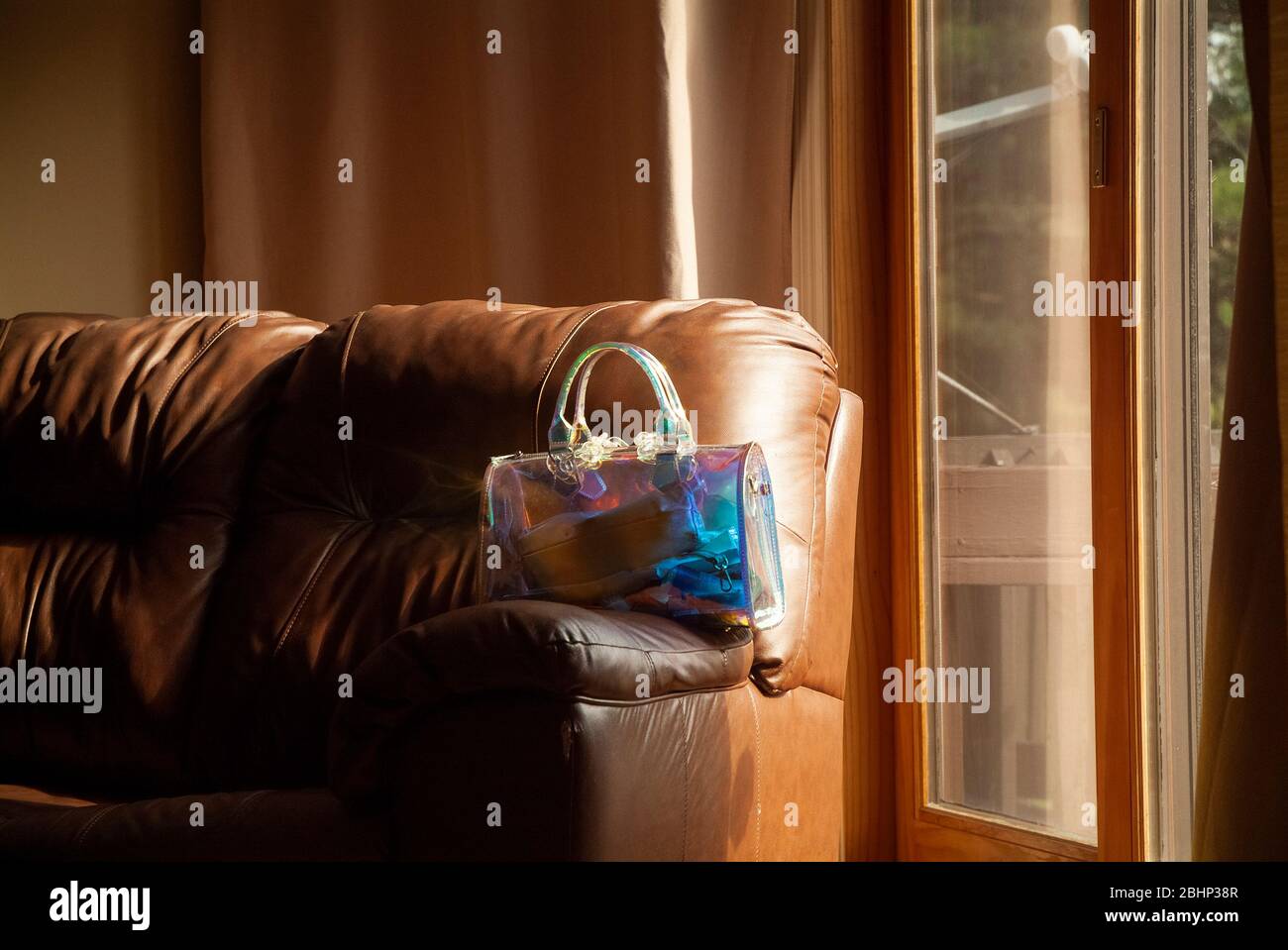 REMINISCENT: A woman's transparent purse rest on the arm rest of a sofa in the living room of a residential home. Stock Photo
