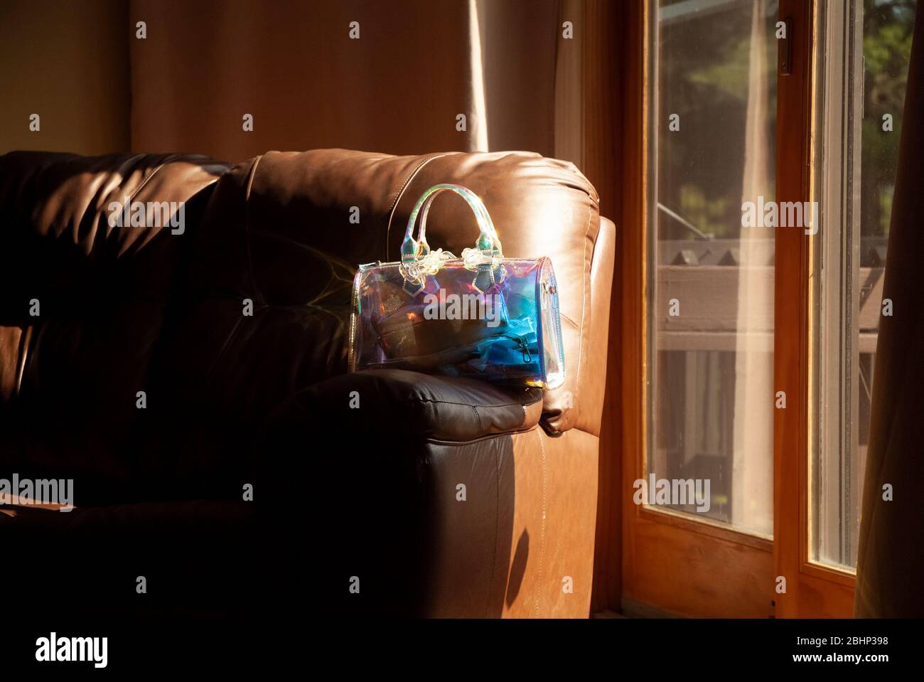 REMINISCENT: A woman's transparent purse rest on the arm rest of a sofa in the living room of a residential home. Stock Photo