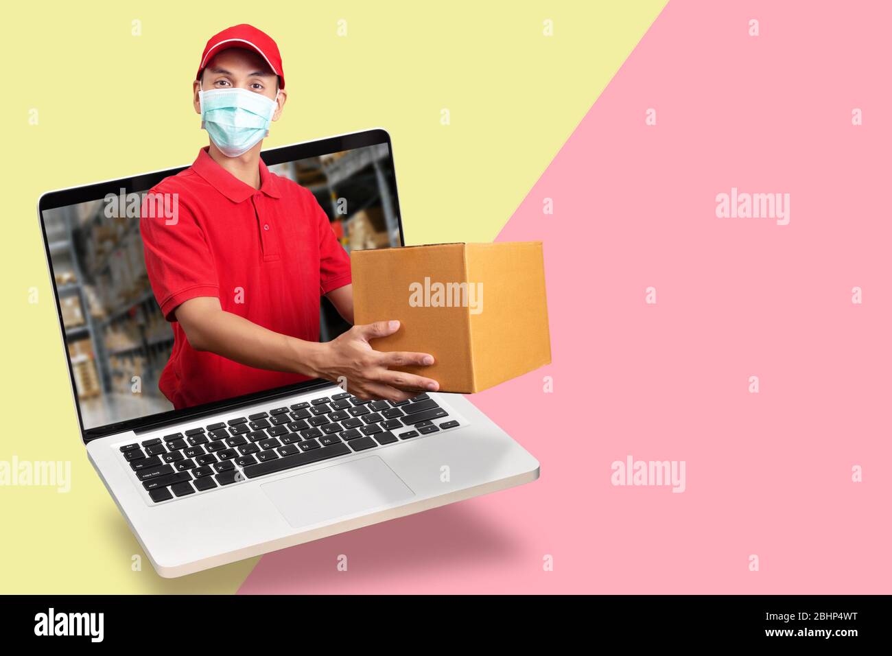 delivery man in red shirt with hygienic mask, holding goods order in package parcel out from laptop computer with warehouse background. order online, Stock Photo