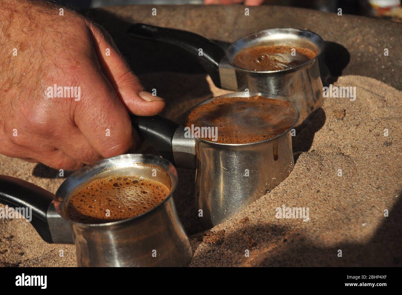 Arabic coffee brewed in a brass metal crucible in hot sand on one of the  street stalls in Aqaba, Jordan. Aroma of coffee with cardamom and sugar for  1 Stock Photo - Alamy