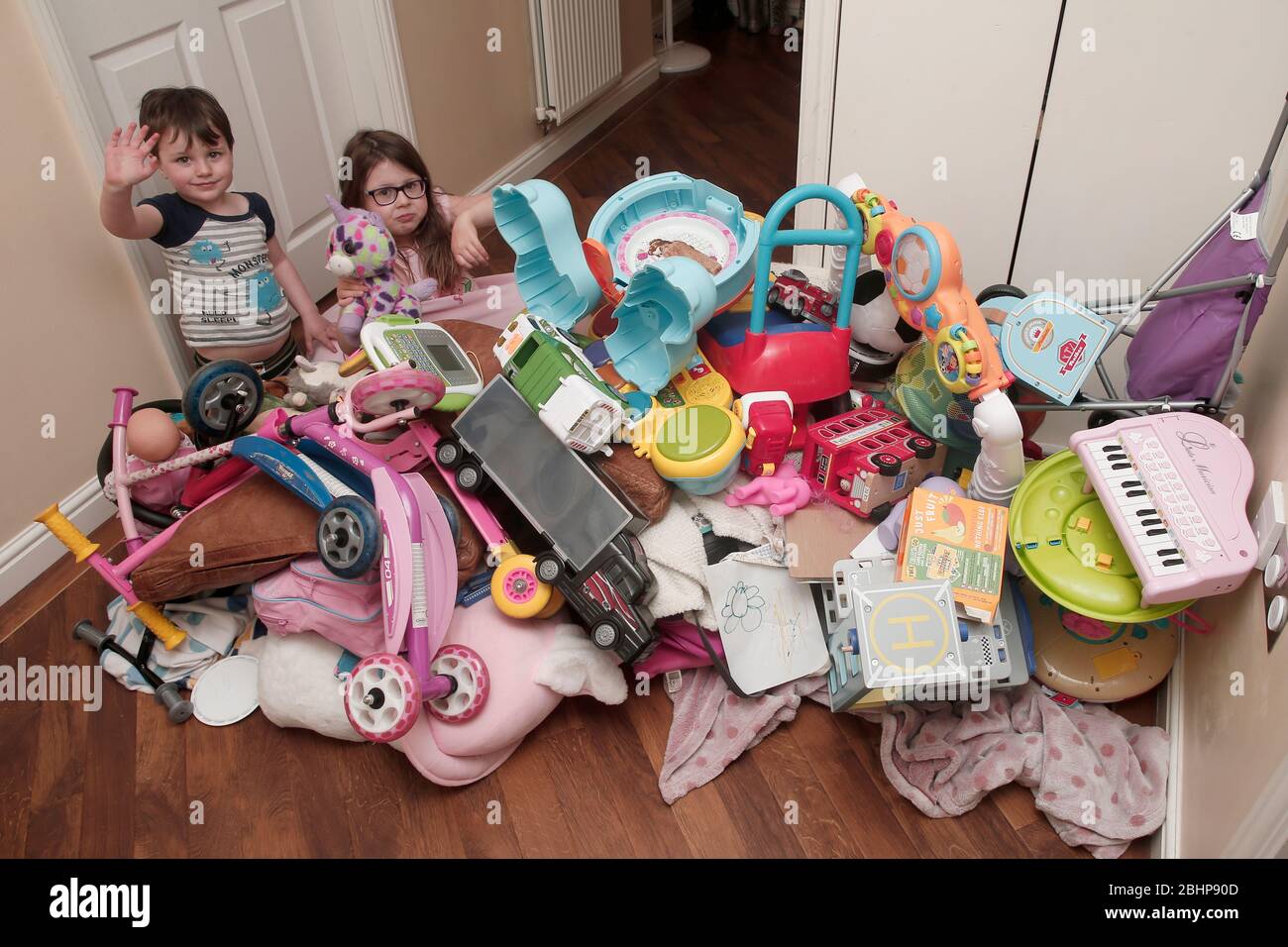 Two siblings surrounded by huge pile of children's toys at home Stock Photo