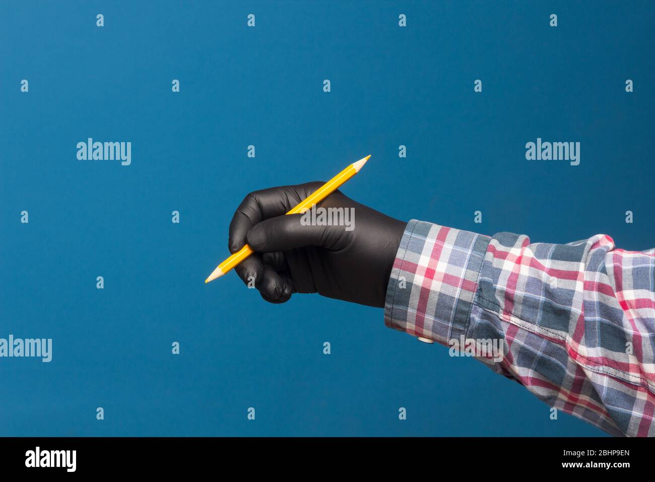 Color pencil with black hygienic protection glove on blue background. Pencil for drawing. pencil with sharp point Stock Photo