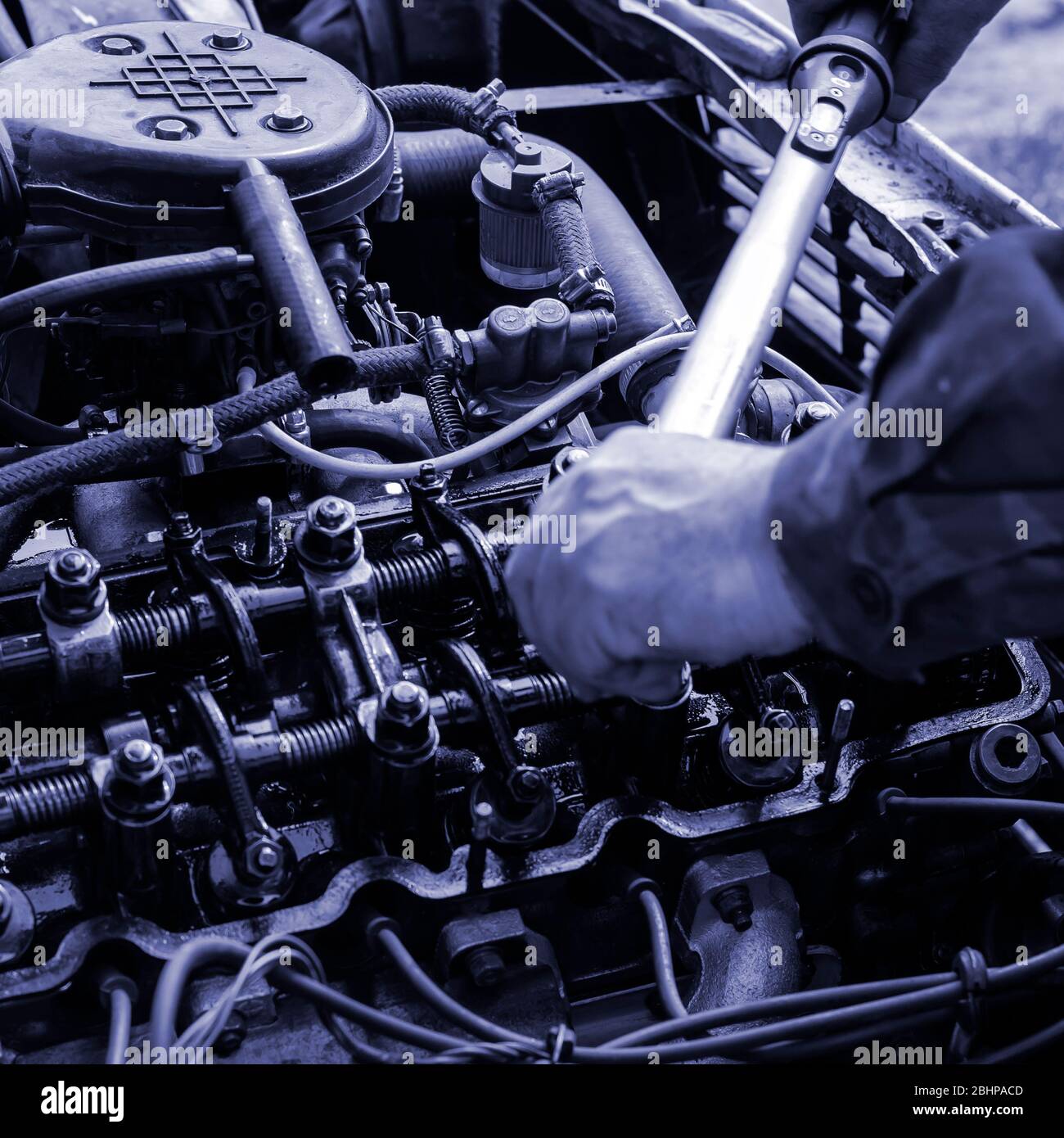 The engine compartment of a passenger car closeup. Tightening the cylinder head. Manual