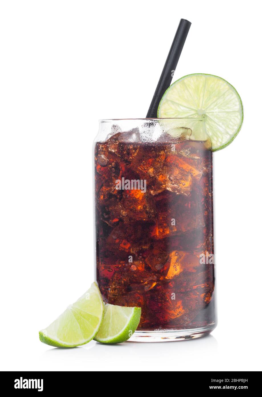 Cuba Libre Cocktail in tin shape glass with ice cubes and slices of lime with straw on white with raw limes background. Stock Photo