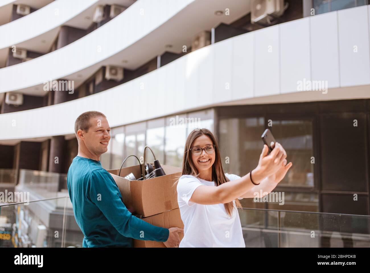 Beautiful caucasian man and woman taking selfies in front of building. Love and moving Stock Photo
