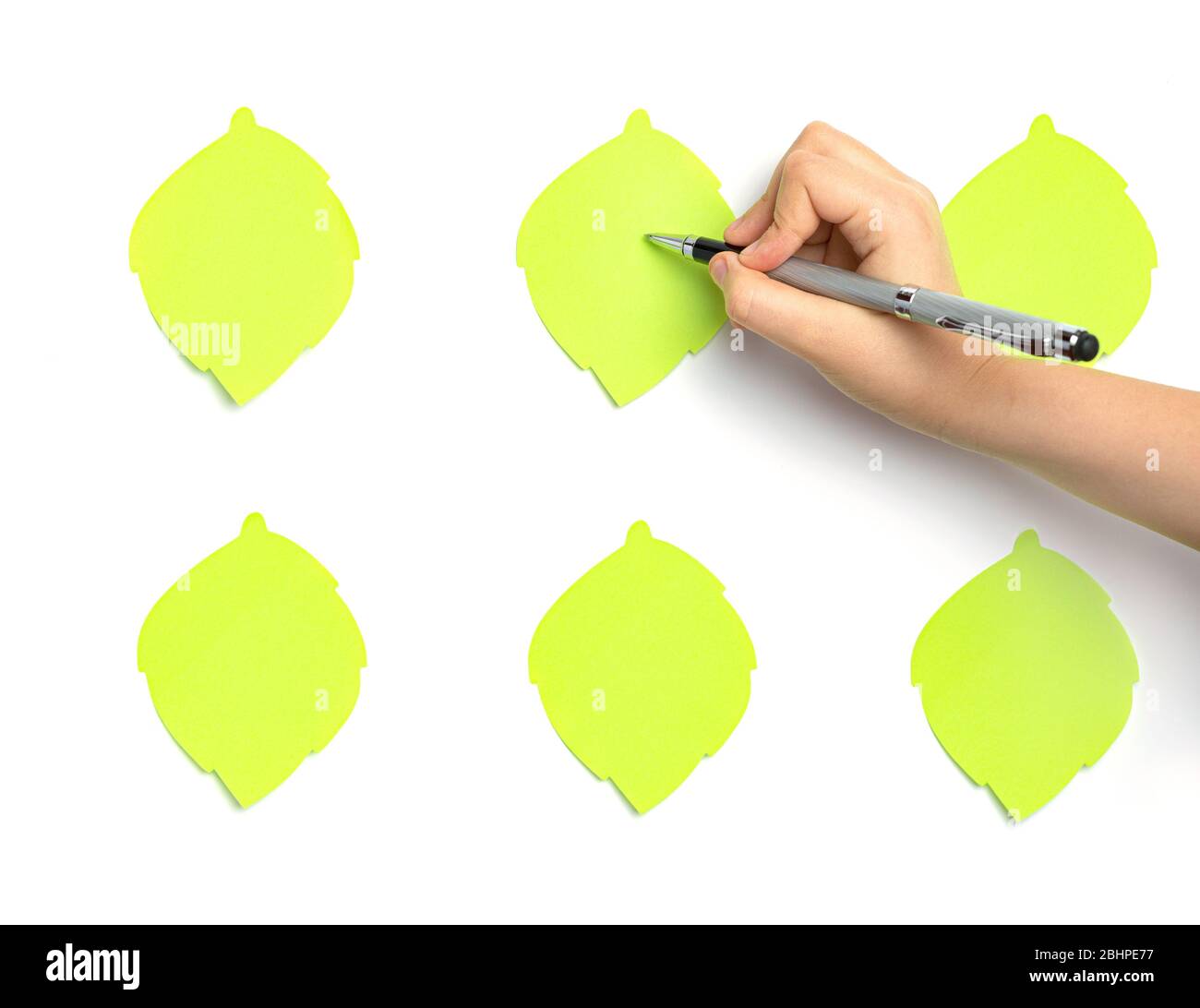 Child's hand writes text on a green sticker. Stock Photo