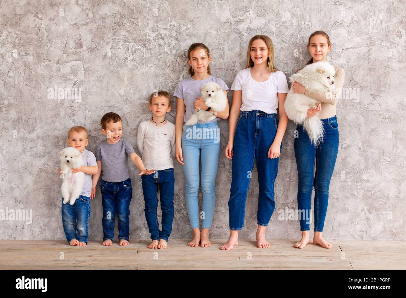 Happy children of different age with puppies standing in line. Teamwork, friendship and togetherness concept Stock Photo
