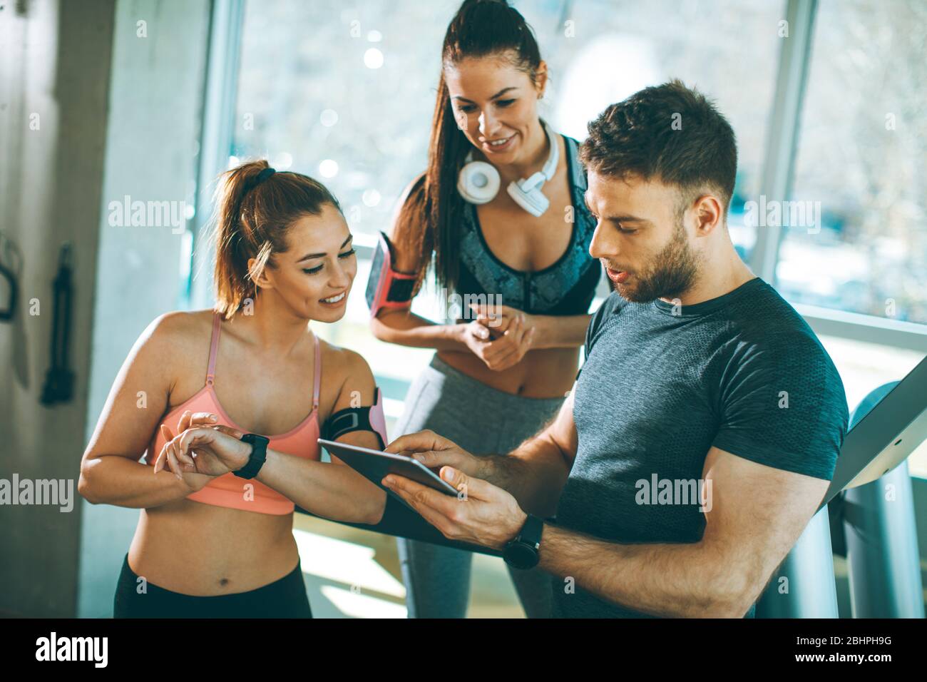 Personal trainer looking at digital tablet and explaining progress to young  women at the gym Stock Photo - Alamy