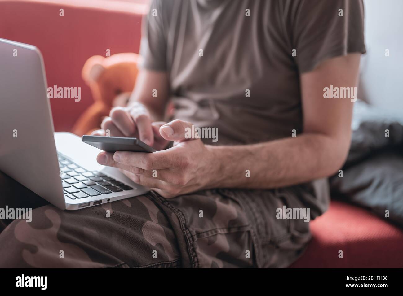 Working from home - telecommuting during covid-19 coronavirus outbreak, man using laptop and mobile phone Stock Photo