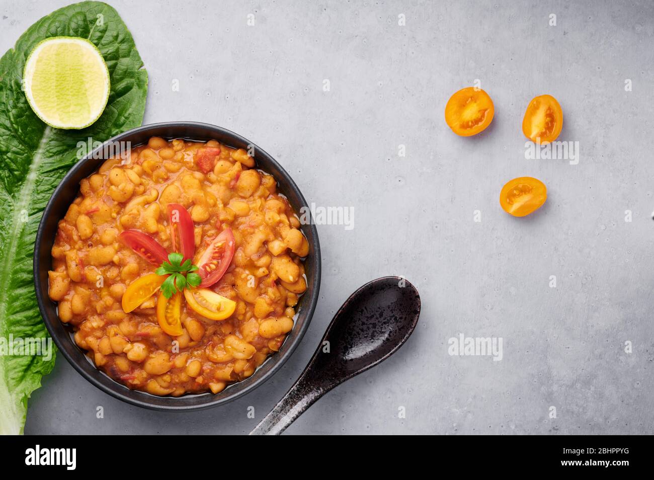 Ful Medames or Fava Beans in black bowl at grey backdrop. Foul Mudammas ...