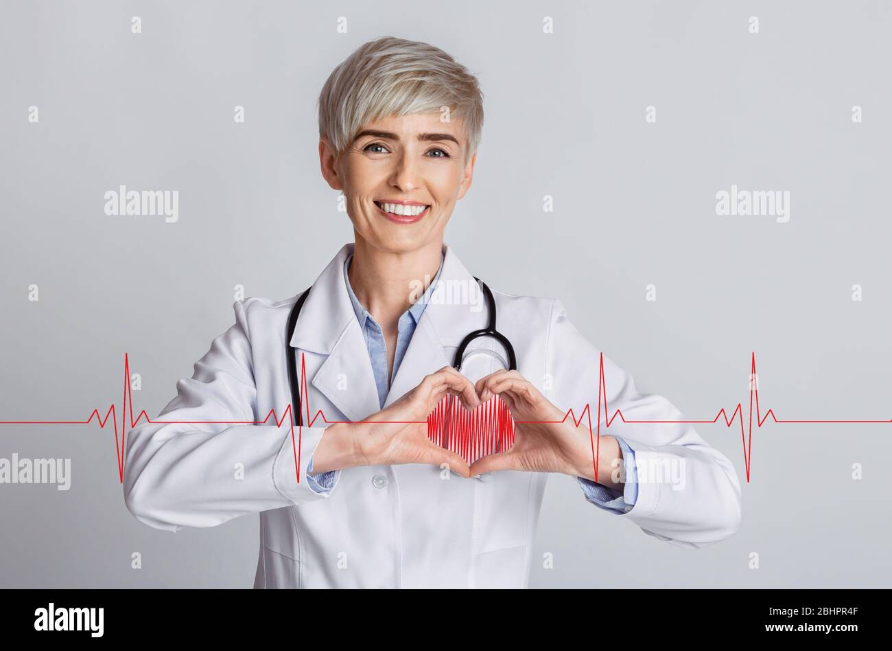 Cardiology concept. Female doctor showing heart with her hands and cardiogram on grey background, collage Stock Photo