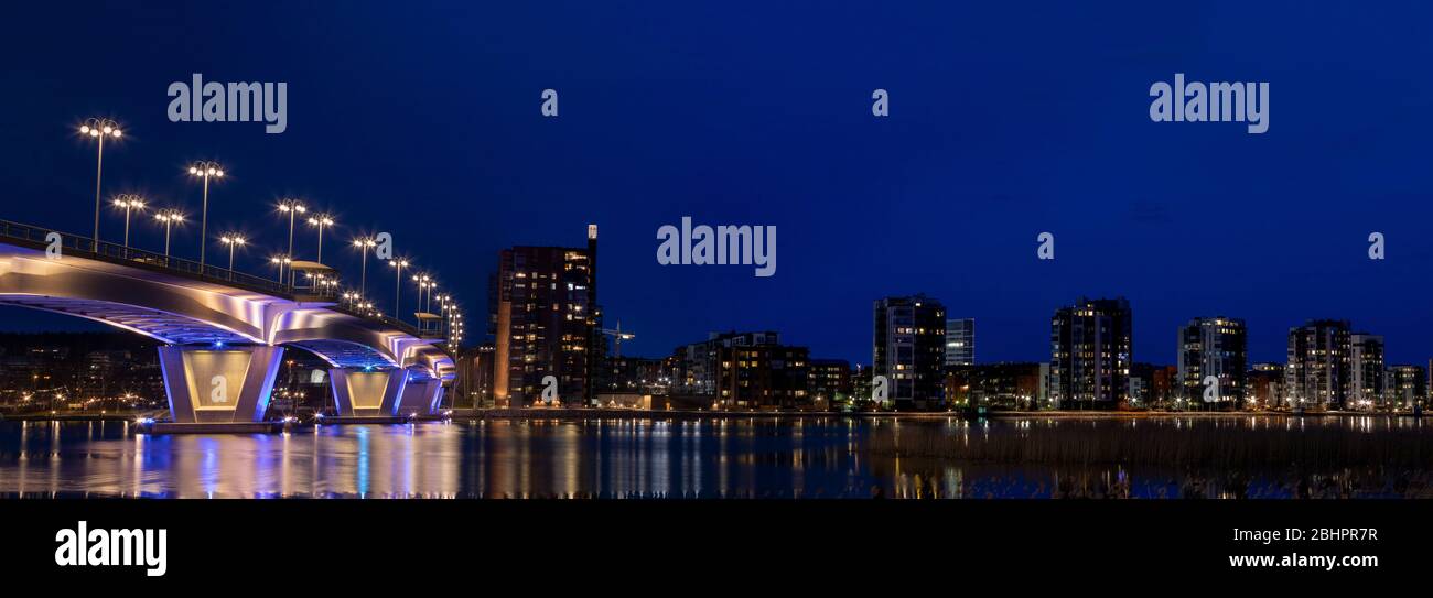 Illuminated bridge and city skyline with still water reflections in Finland Stock Photo