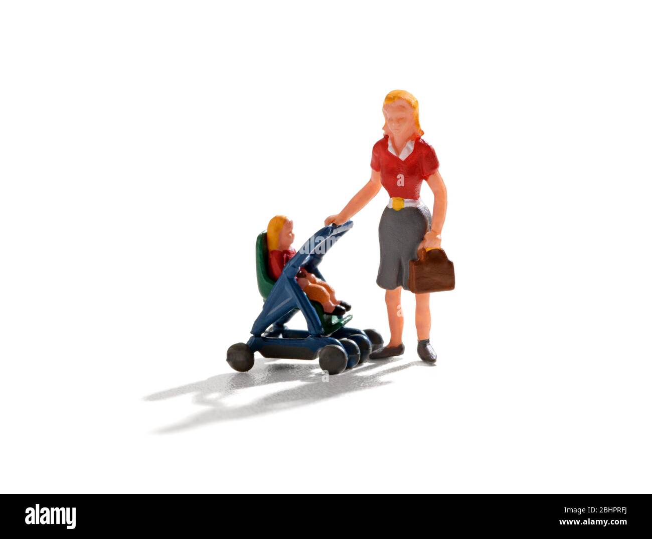 Young miniature mother, child minder or babysitter pushing a baby in a stroller over a white background with copy space and drop shadow Stock Photo