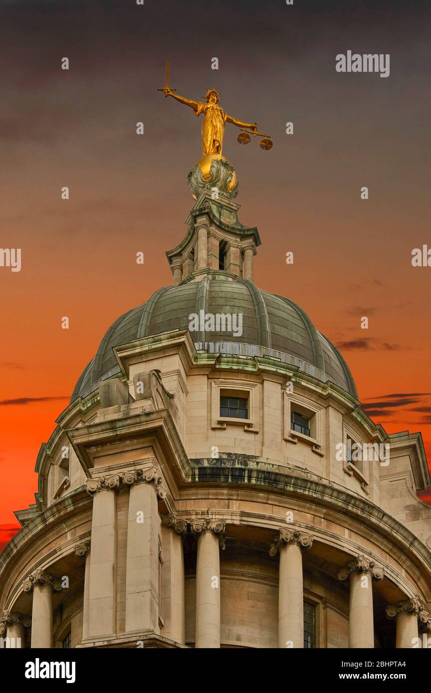 LONDON THE OLD BAILEY CRIMINAL COURT LADY JUSTICE STATUE IN GOLD ON TOP OF THE DOME WITH BLACK AND RED SKY Stock Photo