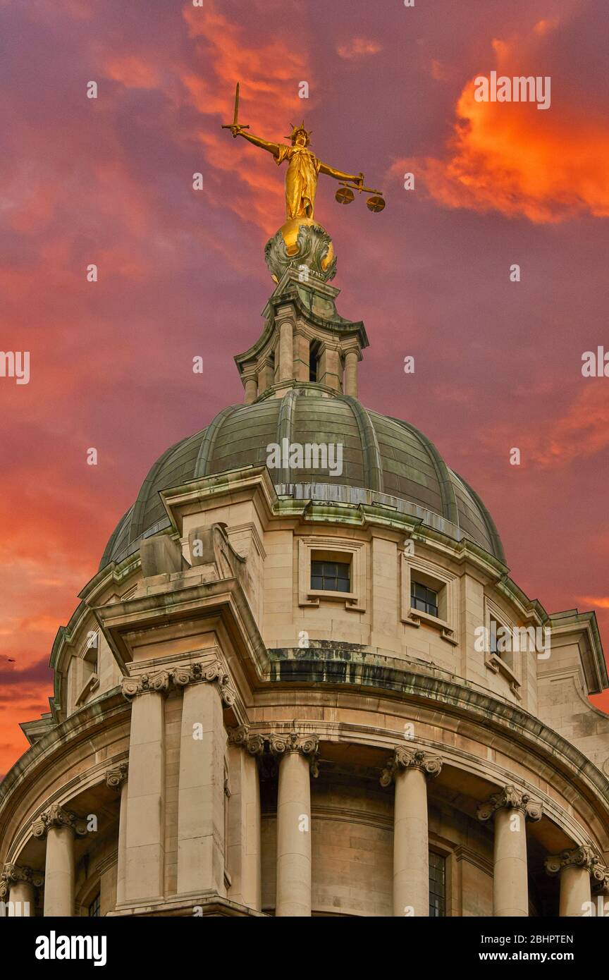 LONDON THE OLD BAILEY CRIMINAL COURT LADY JUSTICE STATUE IN GOLD ON TOP OF THE DOME WITH RED CLOUDS Stock Photo