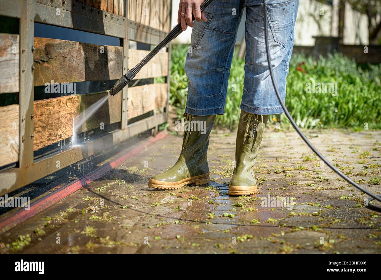 Unrecognizable man cleaning a wooden gate with a power washer. High ...