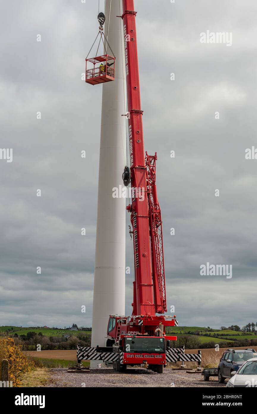 Men using a crane to clean the blades of a wind turbine. Stock Photo