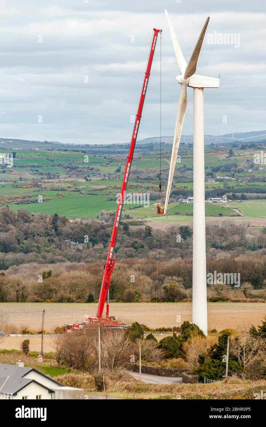 Men using a crane to clean the blades of a wind turbine. Stock Photo