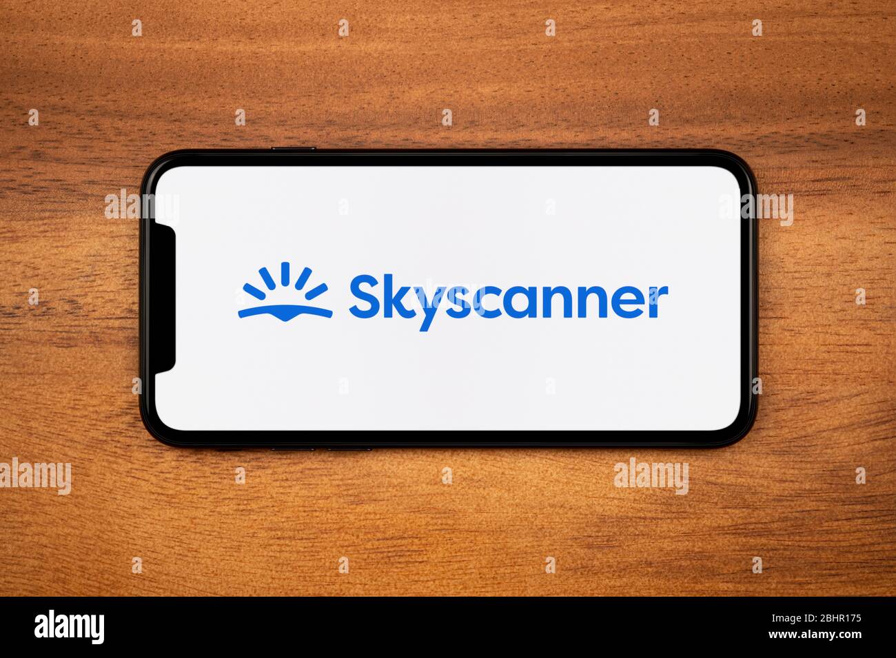 A Smartphone Showing The Skyscanner Logo Rests On A Plain Wooden Table Editorial Use Only Stock Photo Alamy