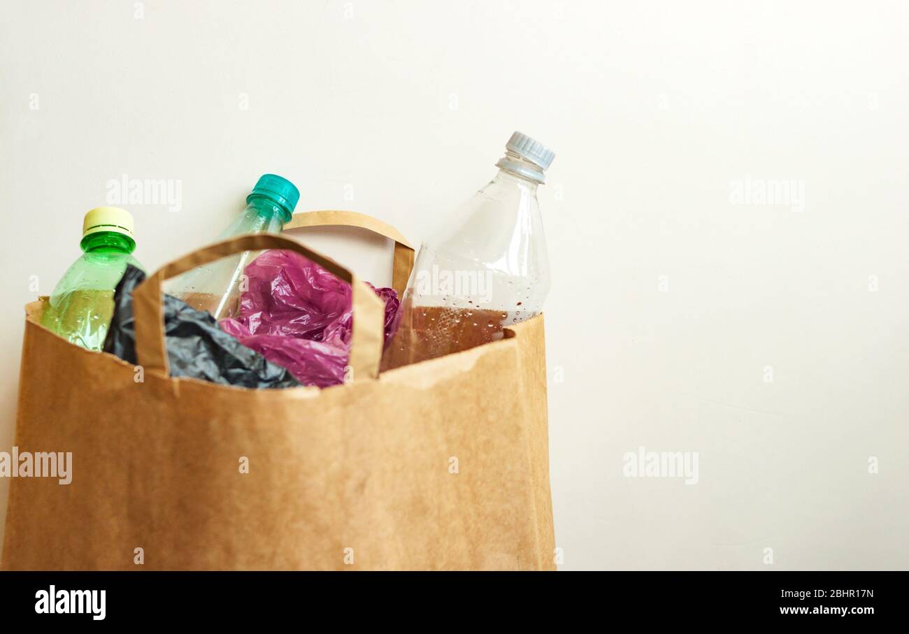 Empty used plastic bottles, bags in brown paper bag, sorting waste for recycling on light background Stock Photo