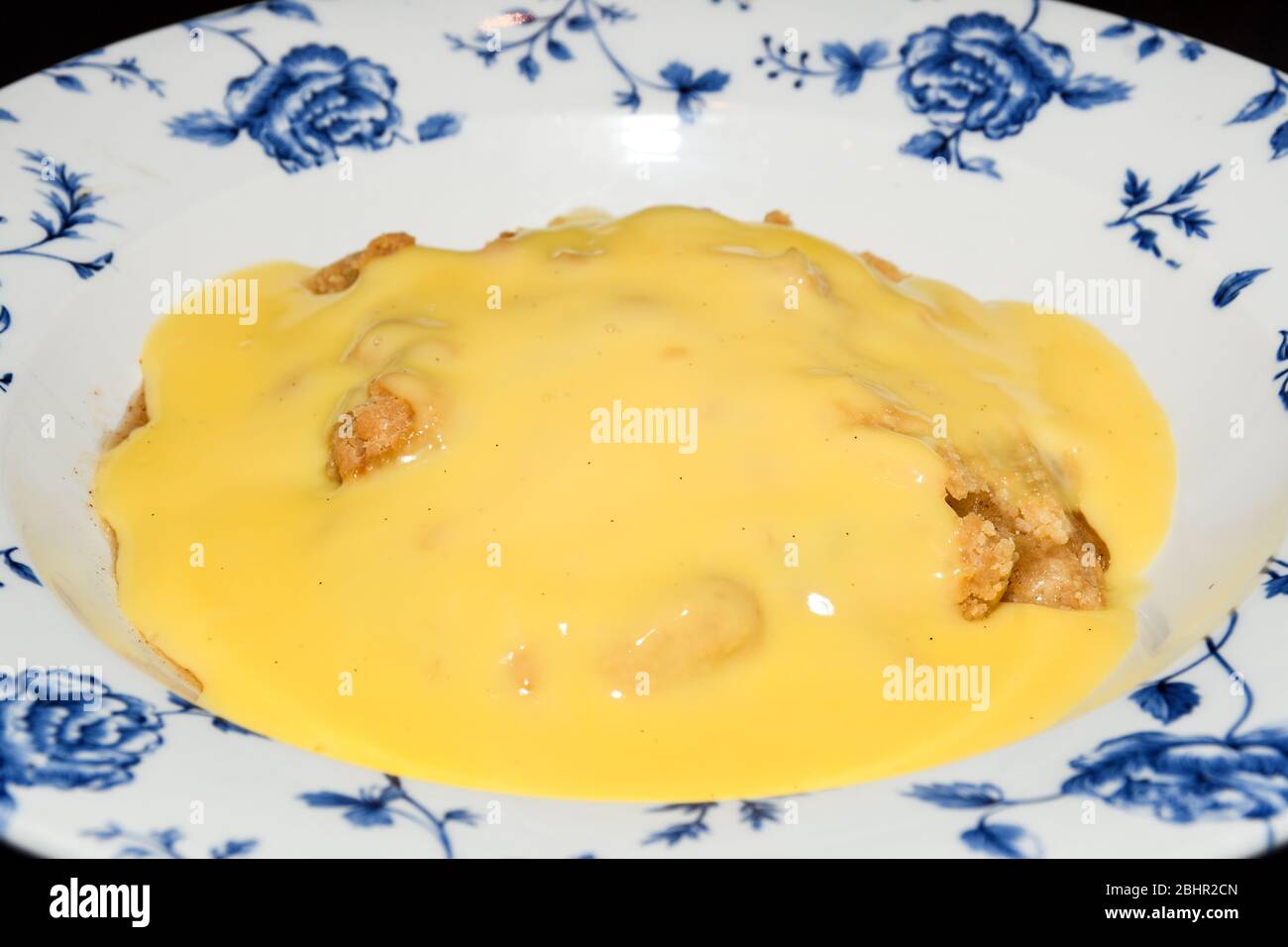 Traditional English apple pie with vanilla pudding on top, served in an