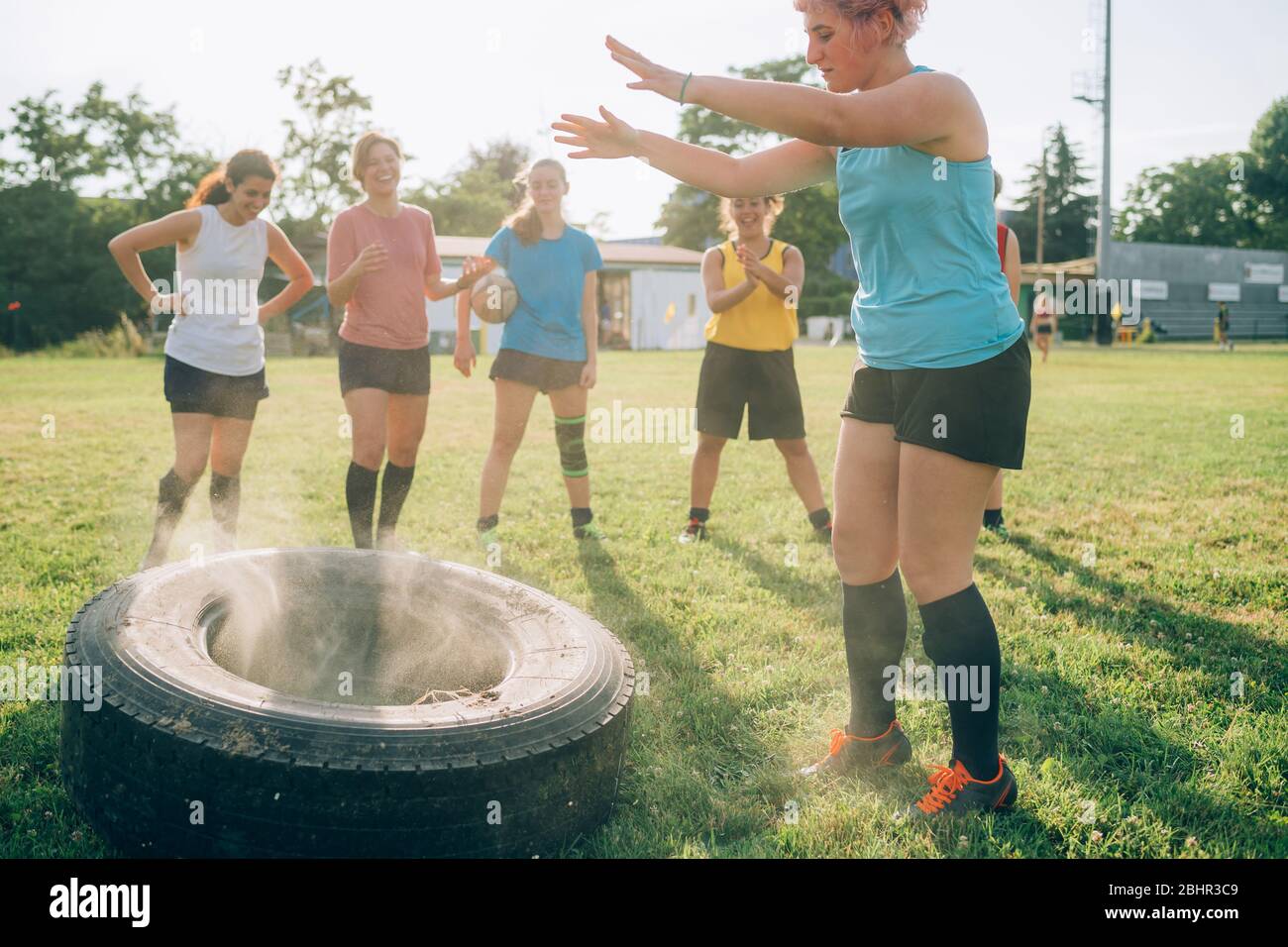 Six women at rugby training one having just thrown a tyre. Stock Photo