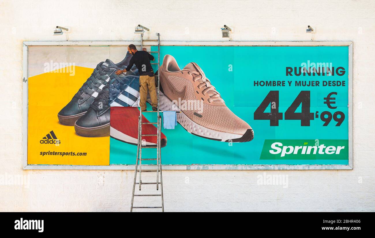 Man on ladder changing a billboard from Nike to Adidas Stock Photo - Alamy