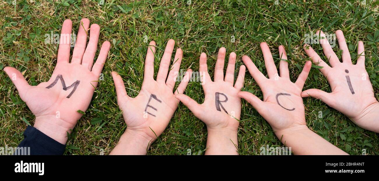 Word merci written on child hands Stock Photo