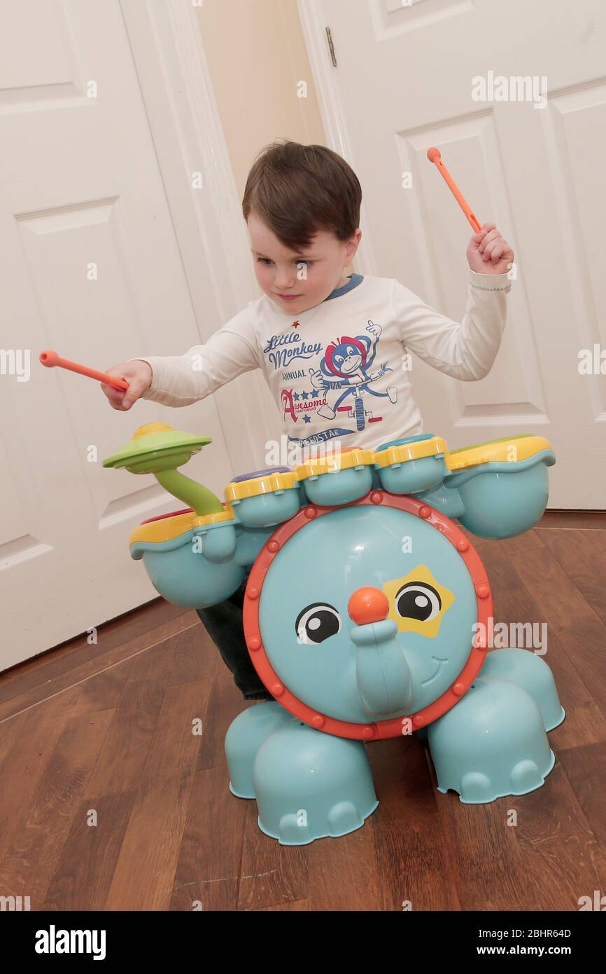 Two year old boy playing the drums at home Stock Photo