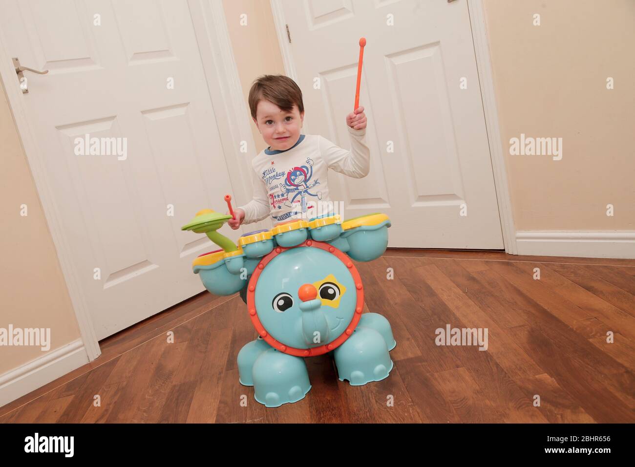 Two year old boy playing the drums at home Stock Photo