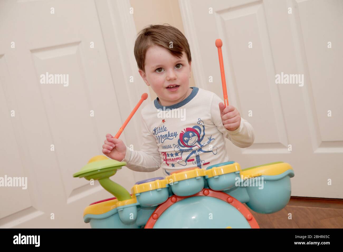 Two year old boy playing the drums at home Stock Photo