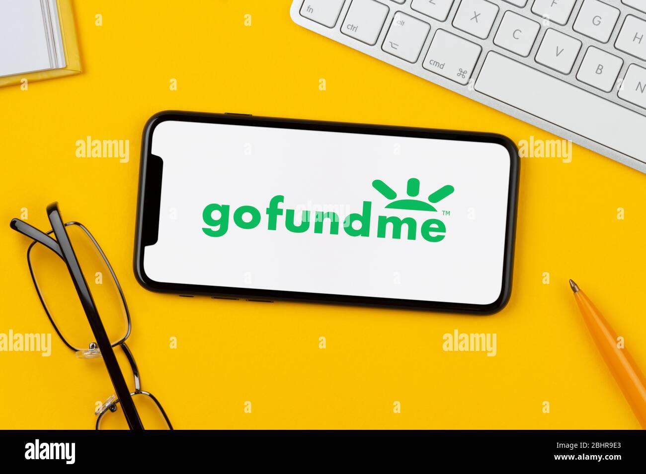 A Smartphone Showing The Gofundme Logo Rests On A Yellow Background Along With A Keyboard Glasses Pen And Book Editorial Use Only Stock Photo Alamy