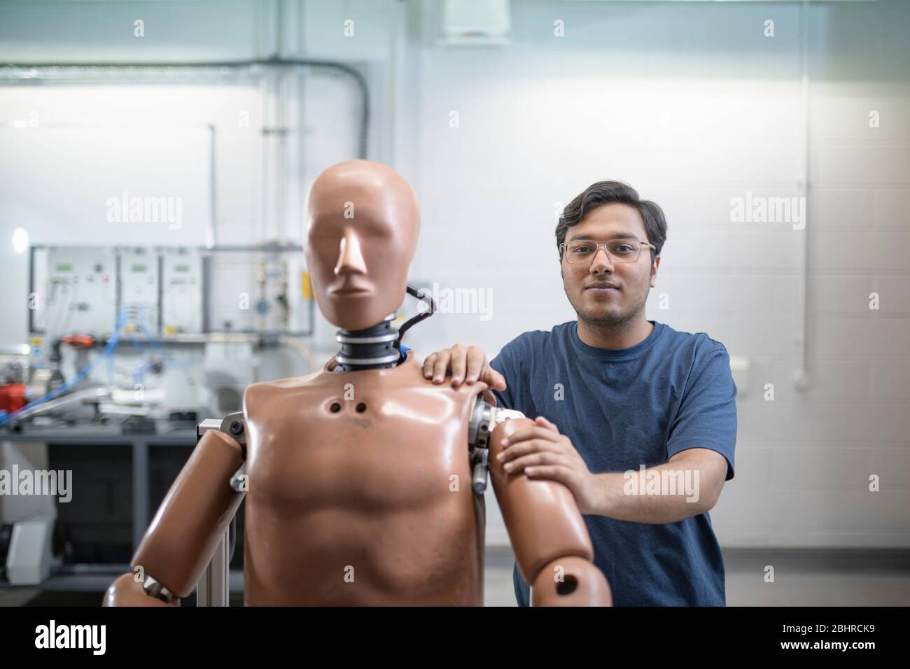 A male student standing behind a test dummy in a workshop. Stock Photo