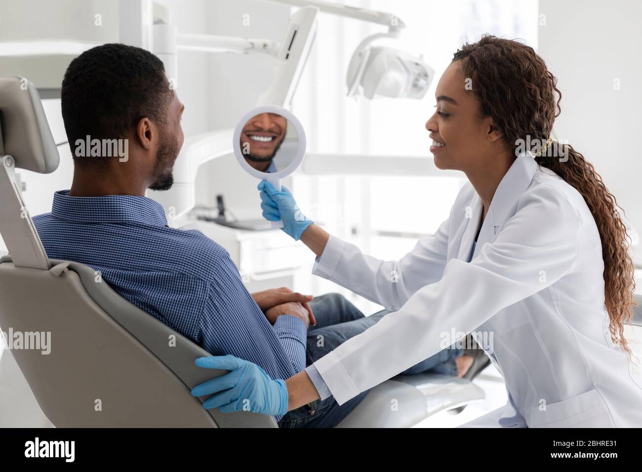 Dentist and patient checking smile in mirror after whitening procedure