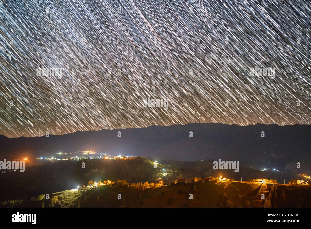 Star trails over the Pestera village in Piatra Craiului mountains from Romania Stock Photo