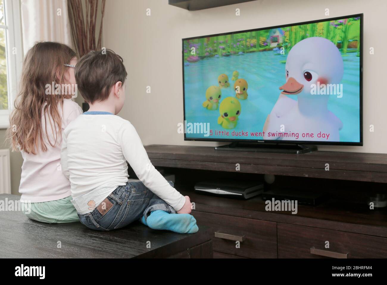 Two siblings watching cartoons on television at home Stock Photo